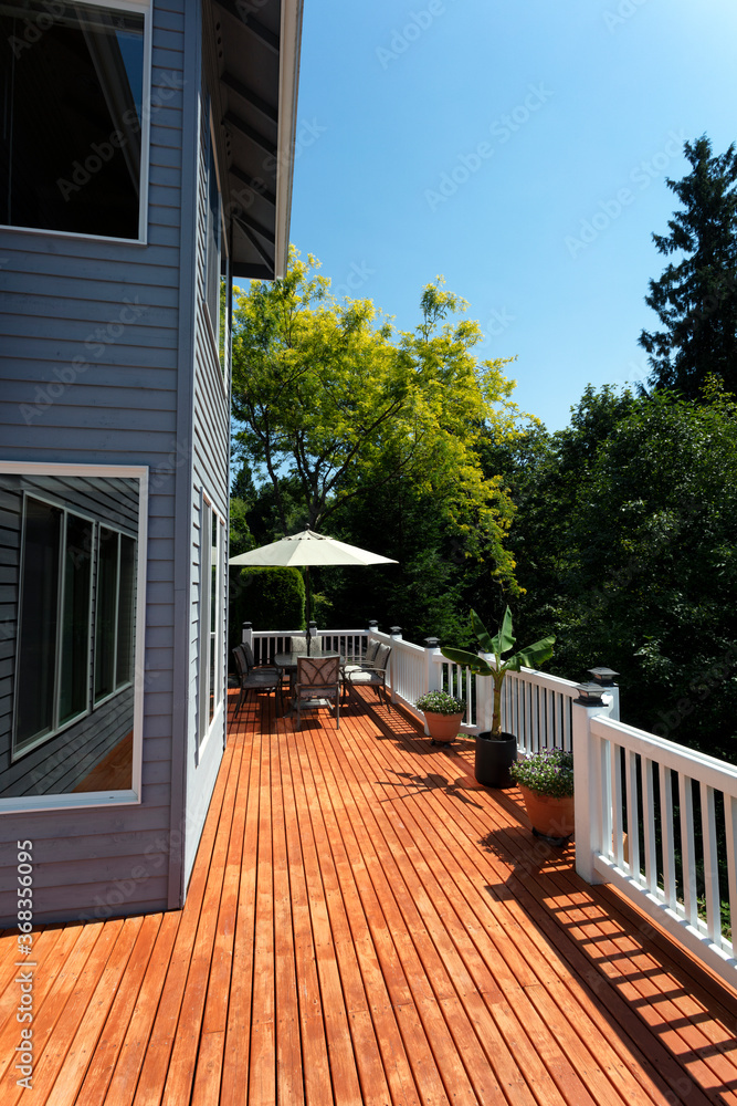 Outdoor home wooden cedar deck during lovely summer day with seasonal garden - obrazy, fototapety, plakaty 