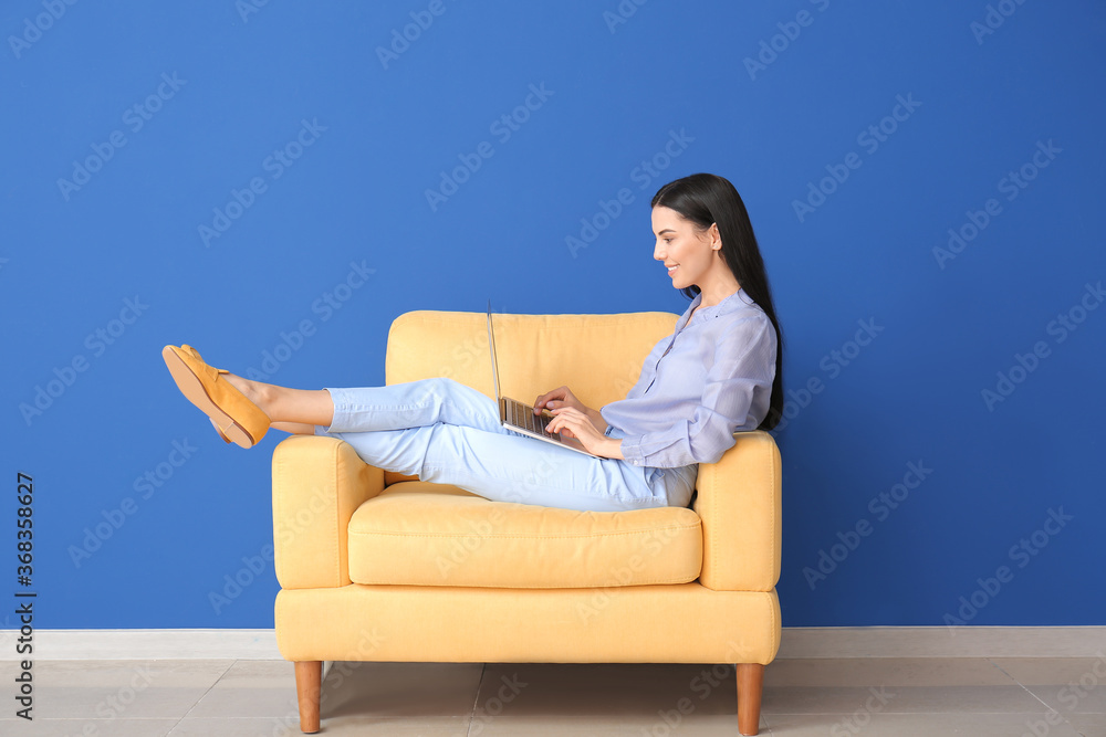 Young woman with laptop relaxing in armchair at home Young woman with laptop relaxing in armchair at home