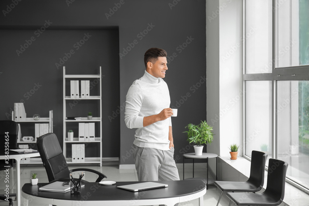 Young man drinking coffee in office Young man drinking coffee in office