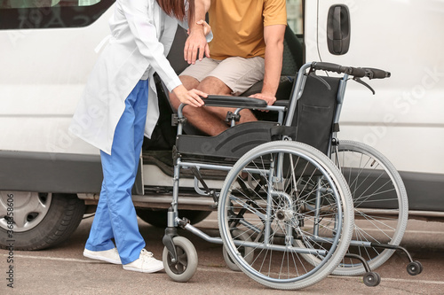 Doctor helping handicapped man to sit in car © Pixel-Shot
