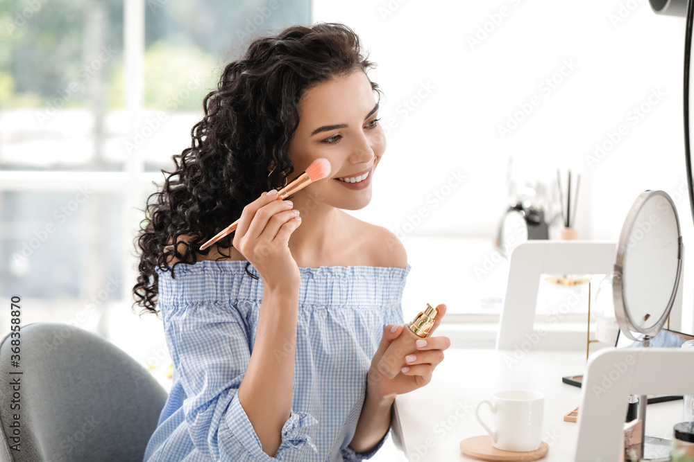 Beautiful young woman applying foundation at home Beautiful young woman applying foundation at home