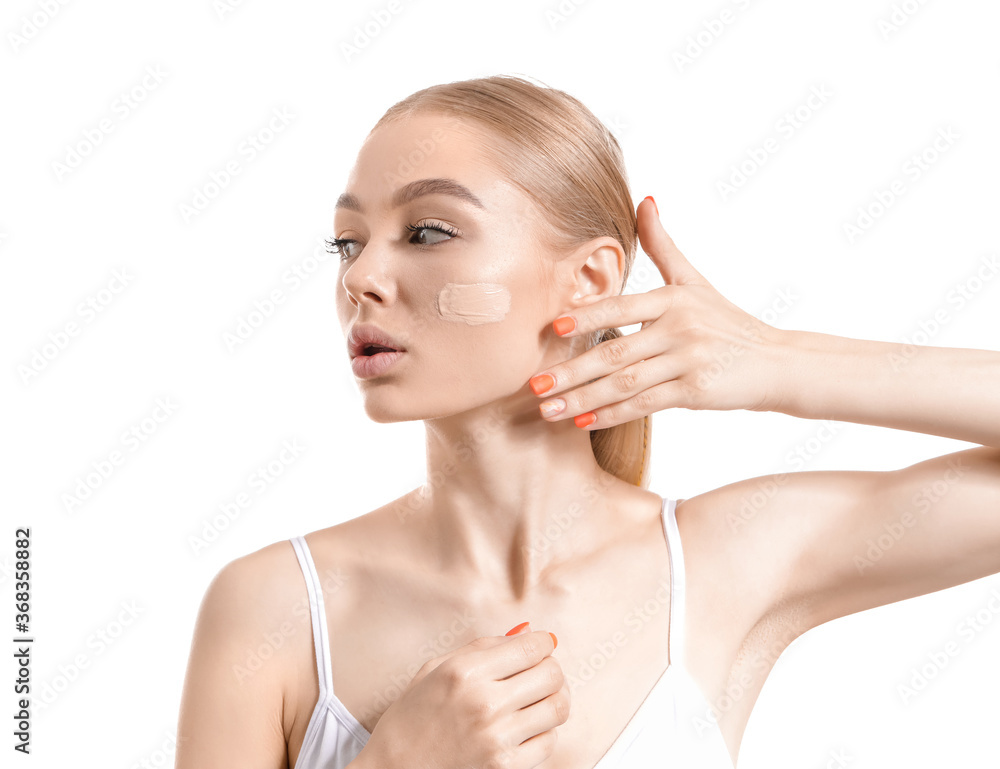 Beautiful young woman with foundation on her face against white background