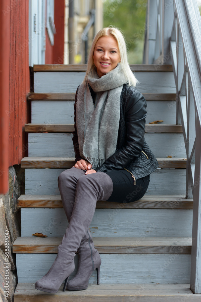 Happy young beautiful blonde woman sitting on wooden staircase outdoors Happy young beautiful blonde woman sitting on wooden staircase outdoors