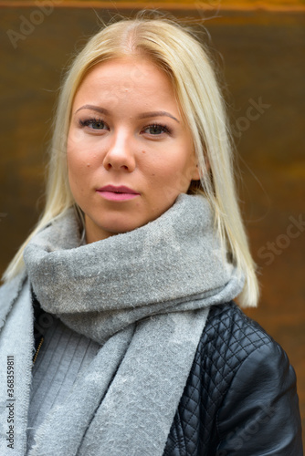 Young beautiful blonde woman against rusty old metal wall