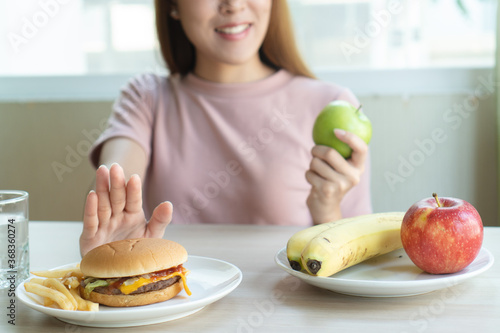 Woman on dieting for good health concept. Woman doing cross arms sign to refuse junk food or fast food (hamburger and potato fried) that have many fat. photo
