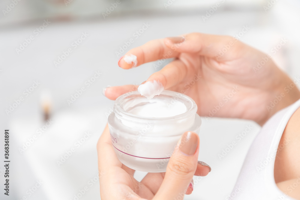 A woman holds a moisturizer in her hand and her skin and wrinkle from impurities. A woman holds a moisturizer in her hand and her skin and wrinkle from impurities.