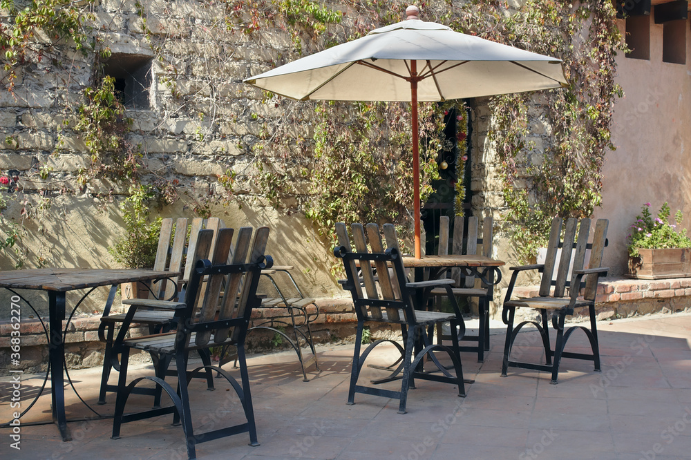 A parasol unmbrella at a beautiful garden with their chairs. A sunny day in the spring with the friends