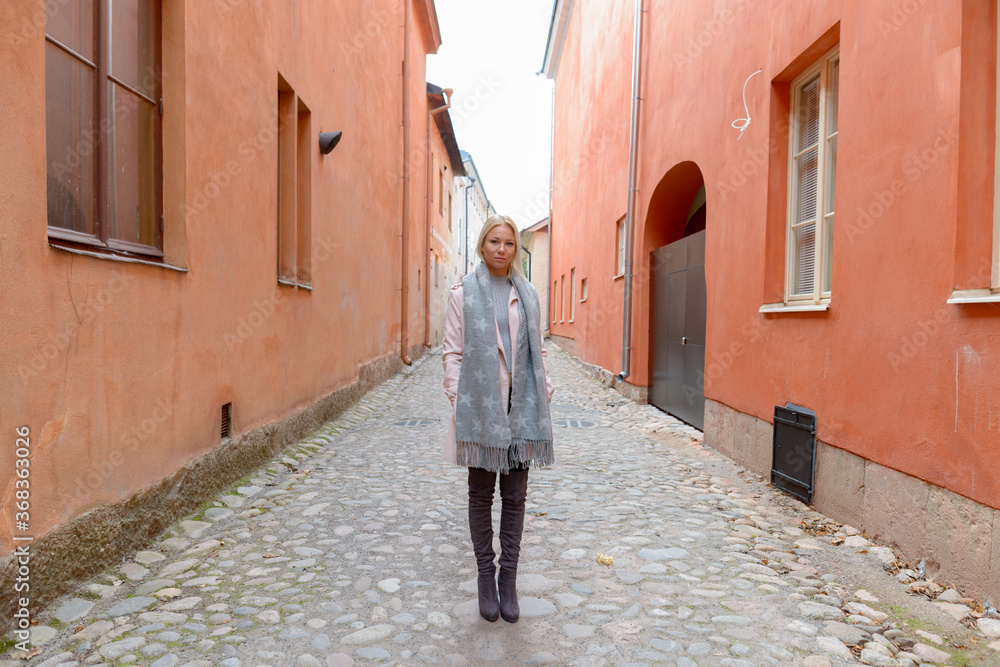 Full body shot of young beautiful blonde woman along the alley in the city