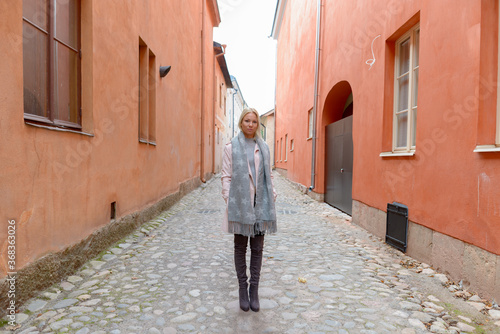 Full body shot of young beautiful blonde woman along the alley in the city © Ranta Images