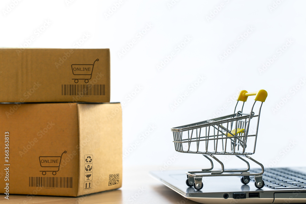 hopping cart or trolley on a notebook computer placed the side the parcel box for delivery to customers. Commercial transactions conducted electronically on the Internet for distance selling. hopping cart or trolley on a notebook computer placed the side the parcel box for delivery to customers. Commercial transactions conducted electronically on the Internet for distance selling.