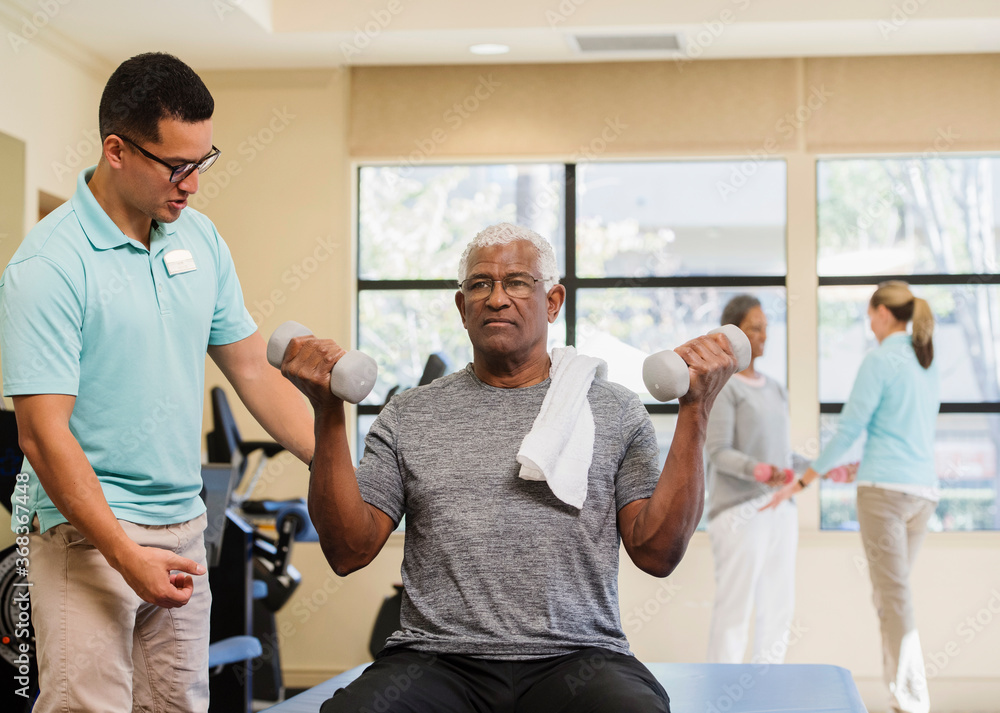 senior couple exercising with trainer in gym senior couple exercising with trainer in gym