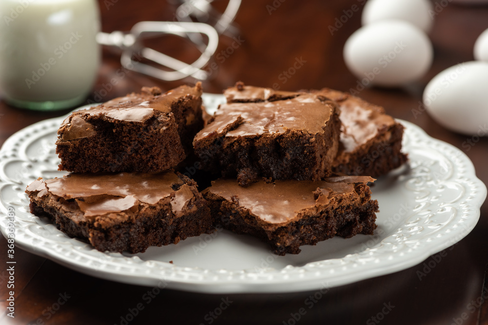 brownies on plate and milk and eggs . background and recipe ingredients on wooden table