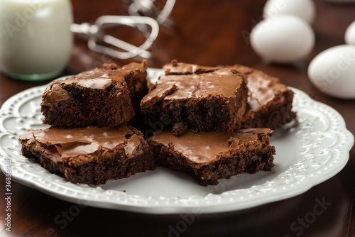 brownies on plate and milk and eggs . background and recipe ingredients on wooden table