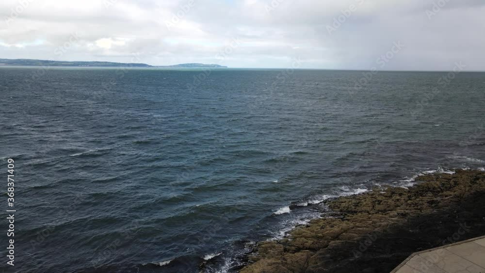 Aerial shot of waves crashing against rocky shoreline on a windy day in Bangor, Northern Ireland Aerial shot of waves crashing against rocky shoreline on a windy day in Bangor, Northern Ireland