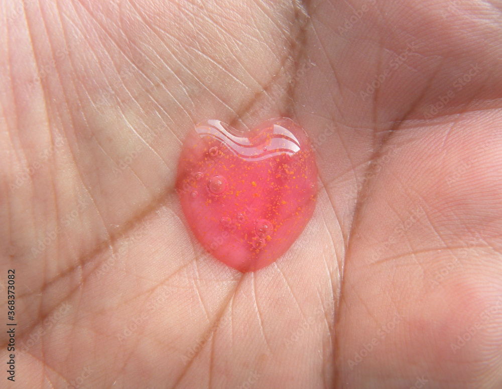 Fototapeta premium Dollop of red color heart shape body wash gel on palm of hand