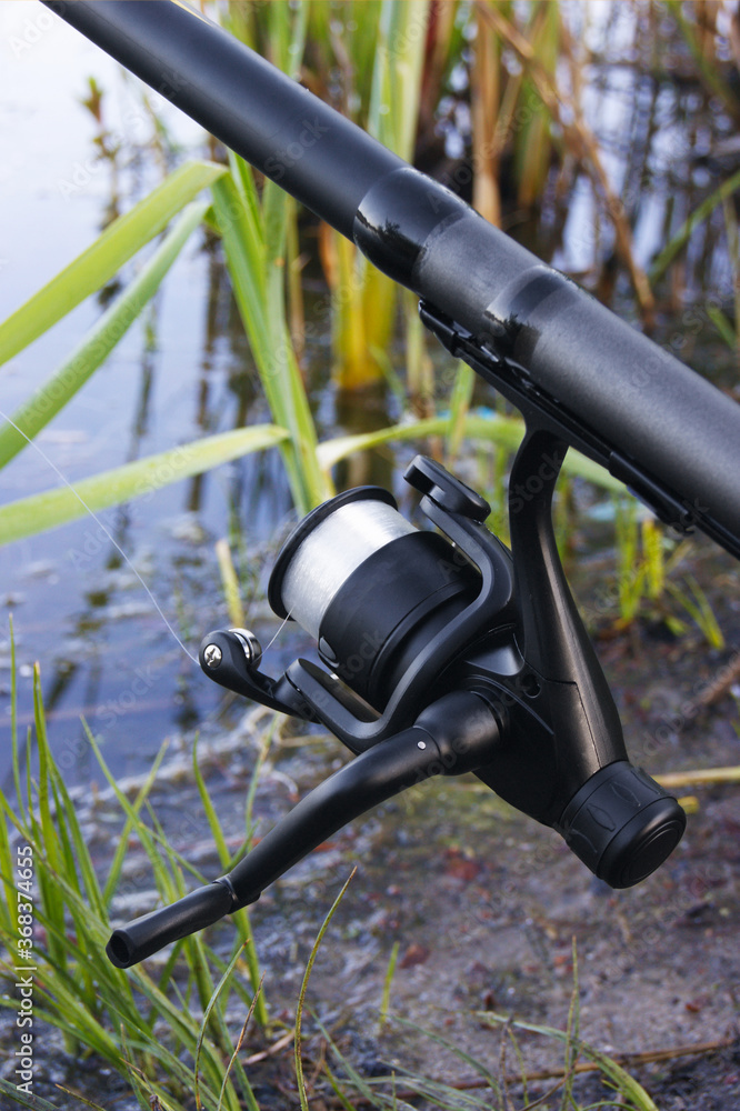 Wheel fishing rod closeup on a lake background.