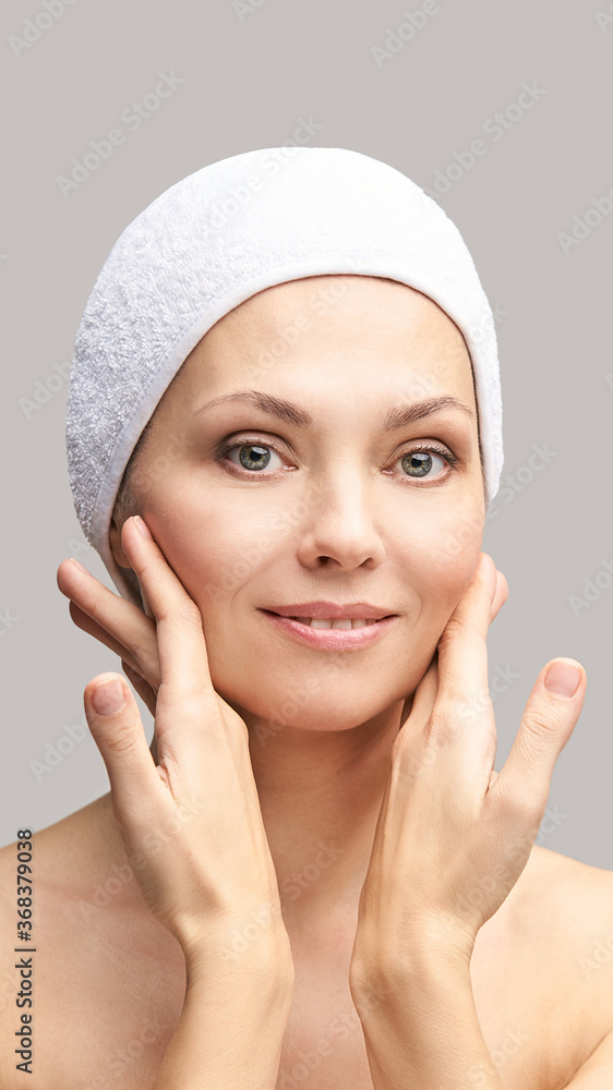 Happy pretty woman. Hands near face. Skincare concept. Home morning routine. Clean skin. Cream cosmetics. Cosmetology therapy. Rejuvenation procedure. Grey background. Copyspace Happy pretty woman. Hands near face. Skincare concept. Home morning routine. Clean skin. Cream cosmetics. Cosmetology therapy. Rejuvenation procedure. Grey background. Copyspace