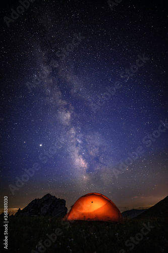The orange tent under the beautiful starry sky glows at night. The orange tent under the Milky way at night.