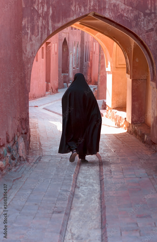 Muslim woman walking on the narrow street  - View on the streets of Abyaneh - The mountain village of Abyaneh in the Barzrud District - IRAN