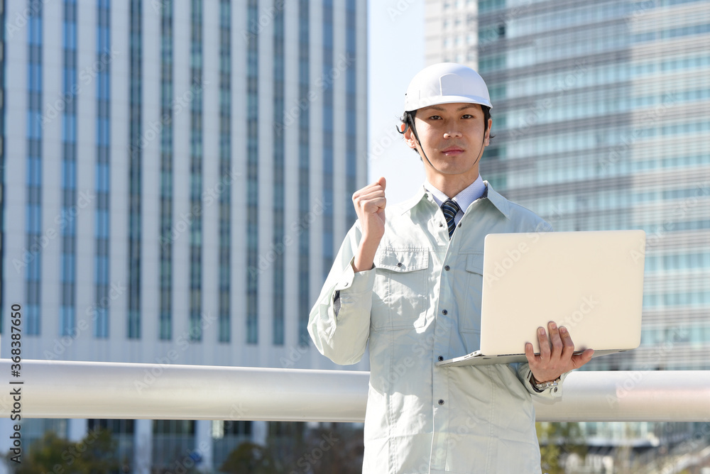 PCを持つ作業服姿の男性