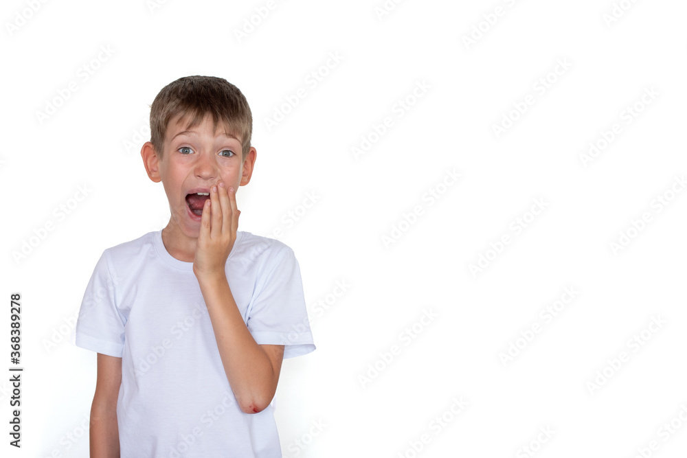 Surprised blond child in a white t-shirt isolated on a white background. Happy child against a white board Surprised blond child in a white t-shirt isolated on a white background. Happy child against a white board