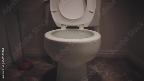 Toilet bowl overflows and water spills over the edge