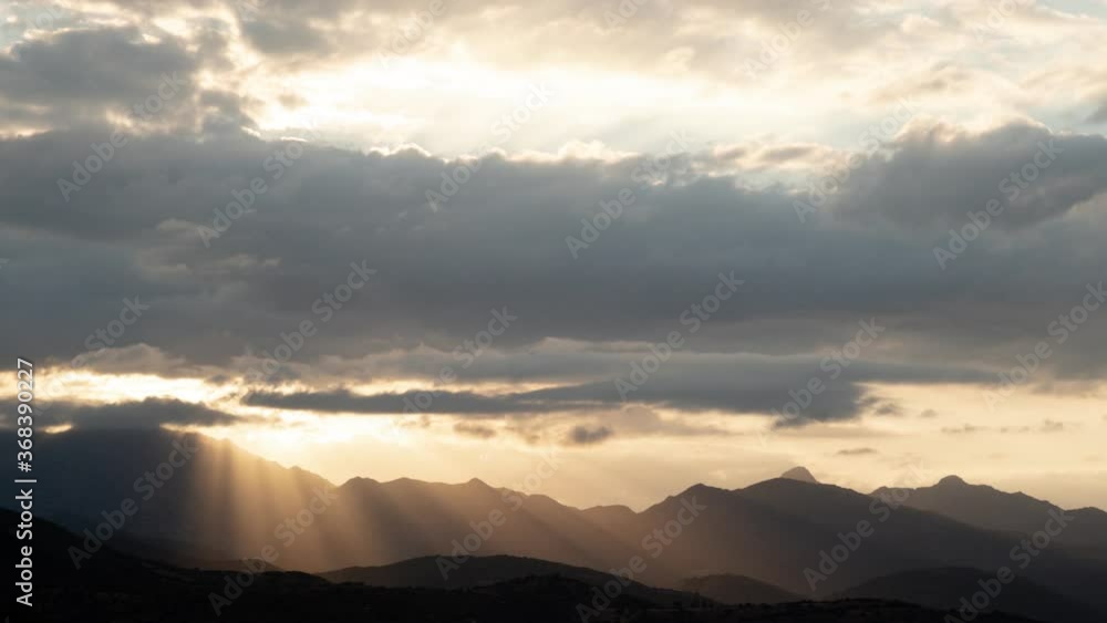 4k uhd dramatic cloudy sunset sky timelapse - The sun's rays infiltrate the black clouds before setting behind the mountains 4k uhd dramatic cloudy sunset sky timelapse - The sun's rays infiltrate the black clouds before setting behind the mountains