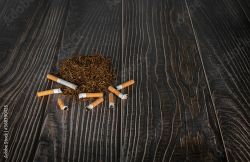 cigarette and cigarette butts on heap of tobacco in a wooden background with copy space.illness concept