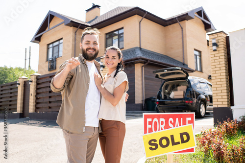 Fotografia Portrait of excited young couple have bought house and showing key to camera, mo