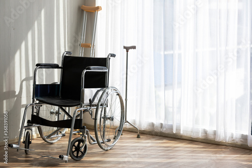 Fototapeta Wheelchair in the room near the window with crutch at behind equipment for patients