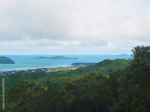 Amazing view from the top of Nakkerd Hills between Chalong and Kata to islands  blue sea  bay. Green forest  rainforest  jungle. Coastal town. Phuket island  Thailand. Sky  clouds. Thai rainy season