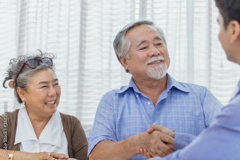 Obraz premium Happy retired Asian senior eldery couple hands shaking business deal and agreement with personal financial advisor or real estate agent. Retirement investment planning with professional counseling.