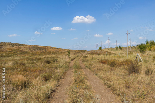 Summer steppe landscape. Landscape in kazakhstan. Kazakh steppe. Power line. Blue sky. Yellow grass. Panorama. Country road