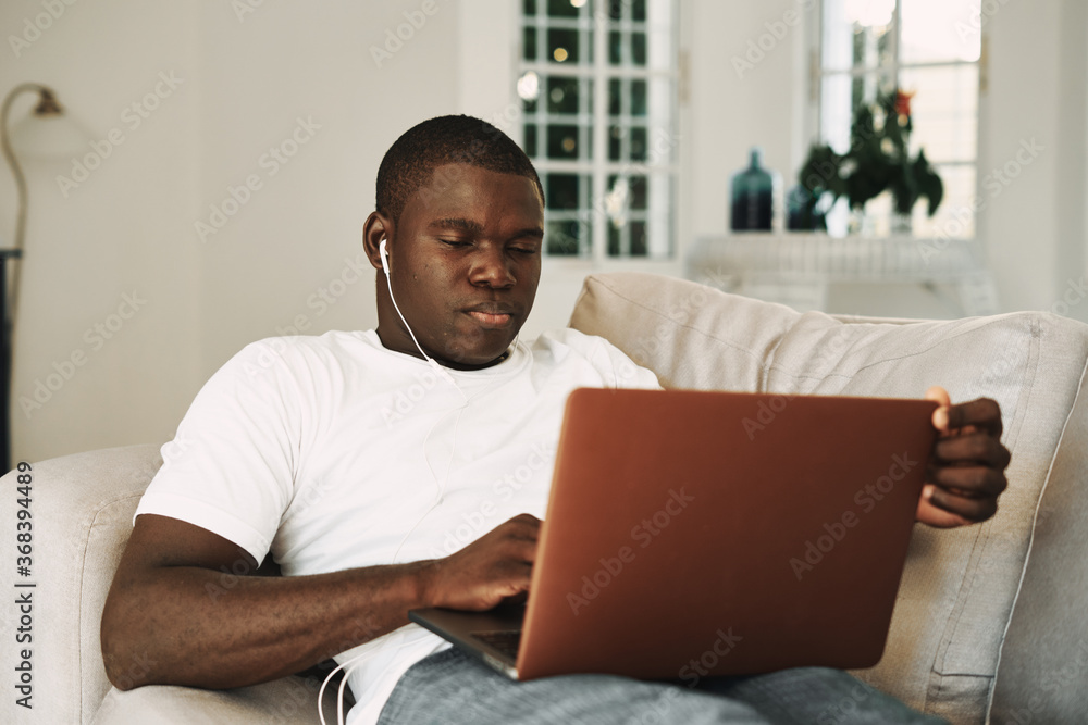 a man lies on the couch with a laptop in headphones technology a man lies on the couch with a laptop in headphones technology