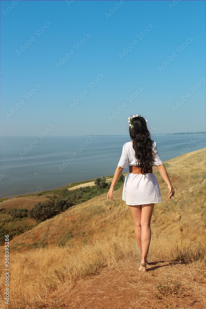 A girl in white clothes walks on a mountain above the sea on a clear Sunny day-A young woman going to the beach - Holiday feelings- A girl in white clothes walks on a mountain above the sea on a clear Sunny day-A young woman going to the beach - Holiday feelings-
