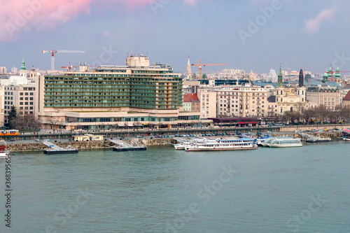 Hungary Budapest March 2018. City view Danube river pier large tourist ship St. Stephen’s Cathedral hotel glass green