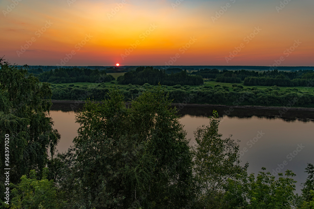Beautiful views of the sunset over the river with trees, fields and flowers