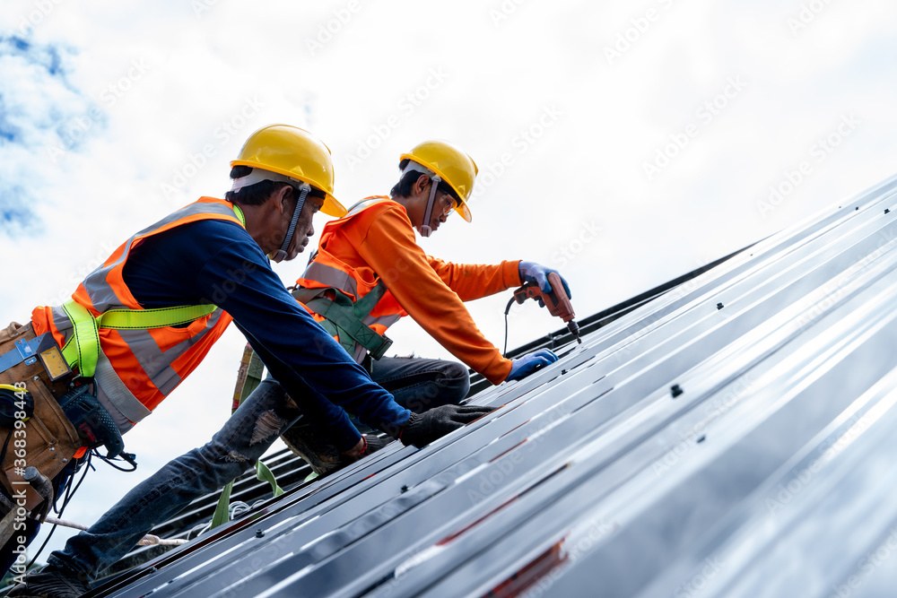 custom made wallpaper toronto digitalClose up photo of Professional and qualified roofer in protective uniform wear use electric drill to install the metal sheet on the new roof at construction site.