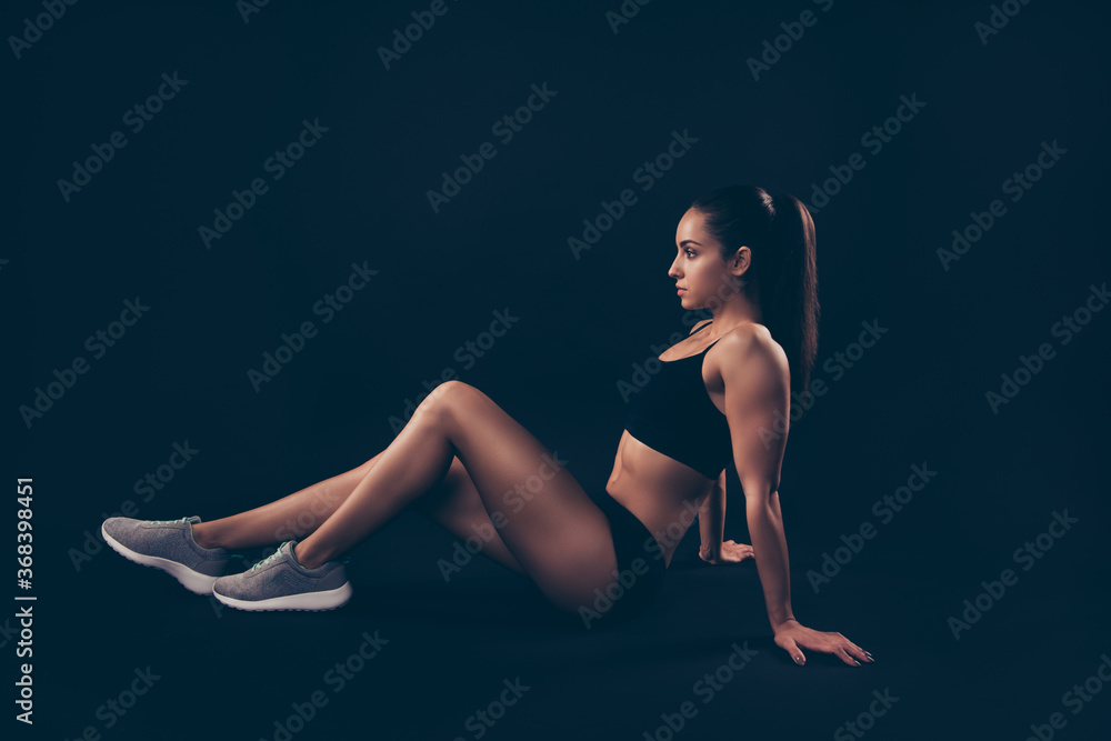 Profile side view of her she nice-looking attractive sportive adorable strong purposeful serious lady sitting on floor perfect form shape figure isolated over black background Profile side view of her she nice-looking attractive sportive adorable strong purposeful serious lady sitting on floor perfect form shape figure isolated over black background
