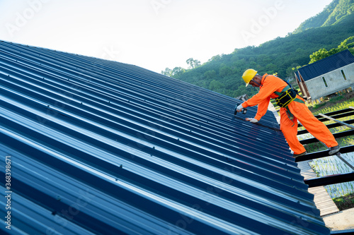 Construction worker install new roof at construction site,Electric drill used on new roofs with Metal Sheet.