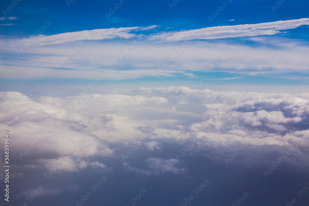 Aerial sky and fluffy clouds background. View from airplane porthole