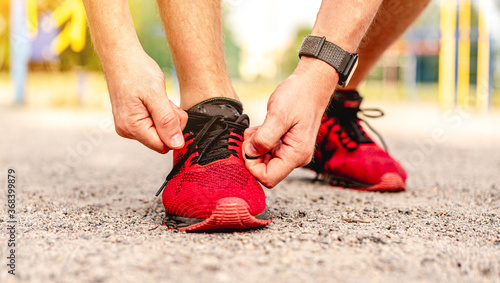 Man tying shoelace on red sneakers photo