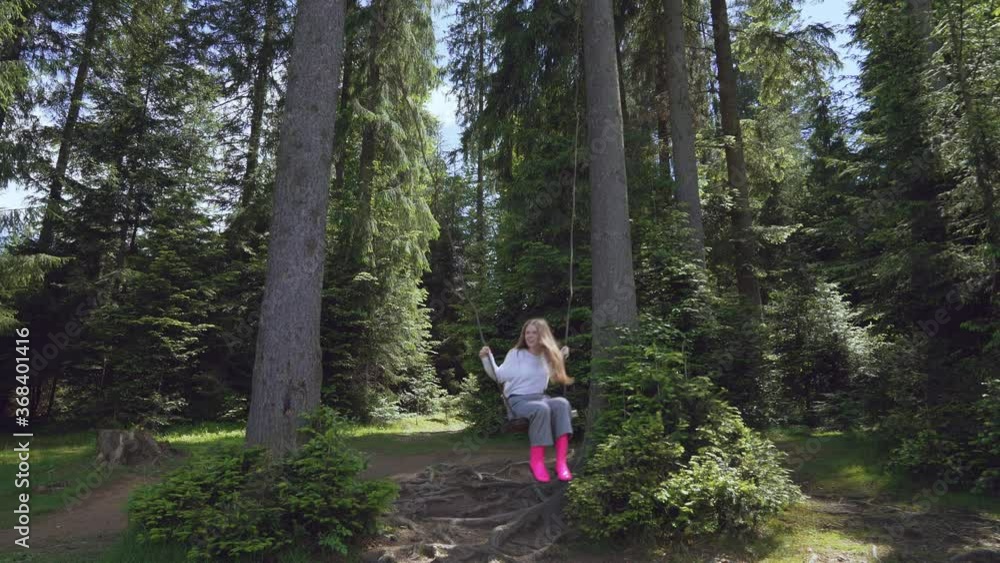 Girl on swing between trees in forest. Girl on swing between trees in forest.