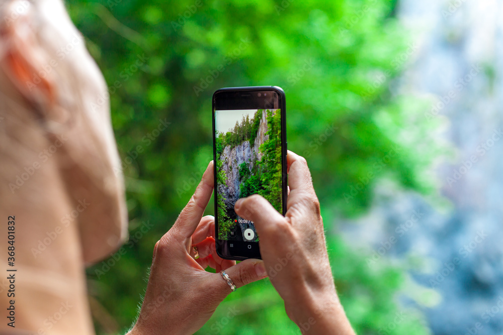 young woman shooting nature video with smartphone