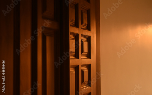Evening sunlight falls on the wooden door which is contemporary styled and contain carvings on it.