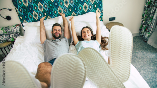 Obraz na plátne Top view photo of the funny excited happy couple in love are lying on the bed in