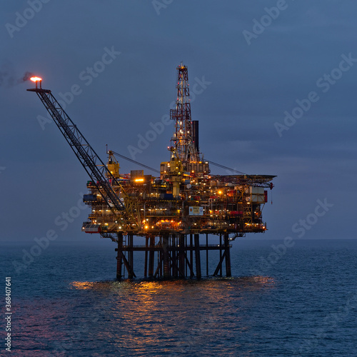 Canvastavla The Gannet A Oil Platform in the twilight of a Summers evening in a very calm North Seam with its lights on, and flare stack burning