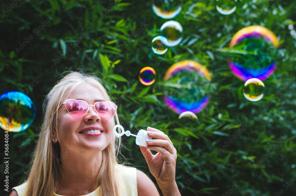 Young woman blows bubble blower in the street. Close-up portrait. Happiness and positive emotions concept Young woman blows bubble blower in the street. Close-up portrait. Happiness and positive emotions concept