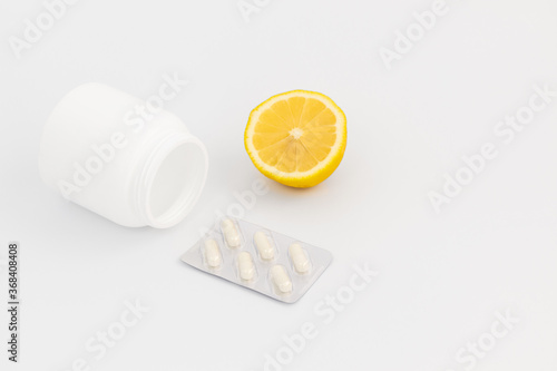 Jar with pills, lemon and a blister on a white background.