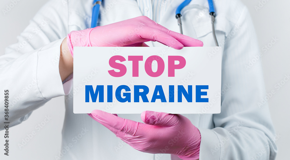 Cropped view of young female doctor in a white coat and pink sterile gloves holding a card with text STOP MIGRAINE. Medical concept. Cropped view of young female doctor in a white coat and pink sterile gloves holding a card with text STOP MIGRAINE. Medical concept.
